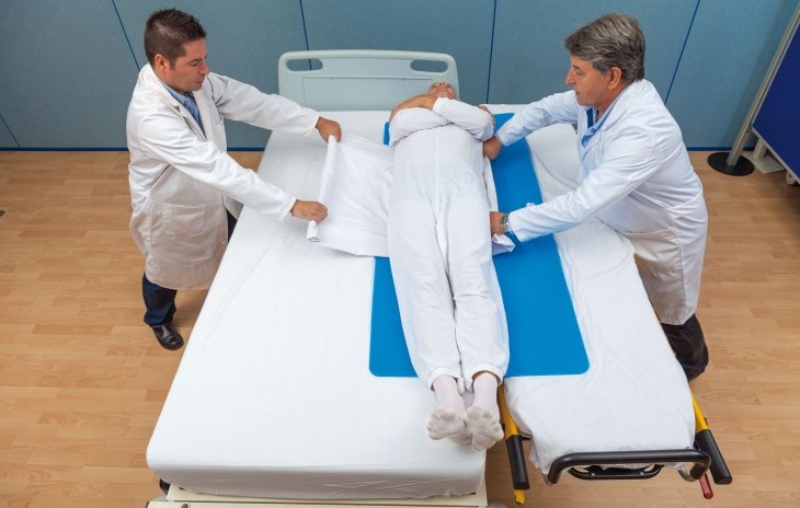 due infermieri operano un trasferimentoda letto a barella di una persona stesa