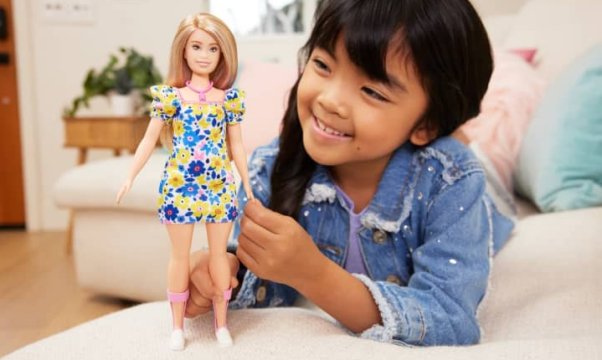 bambina gioca con una barbie con  sindrome di down