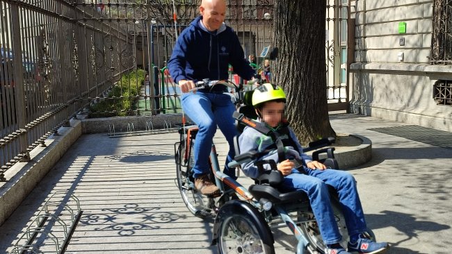 signore guida una bicicletta adattata per ospitare anche un bambino con disabilità a bordo 