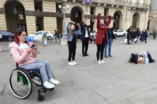 alcune persone, tra cui una in carrozzina, partecipano al flashmob tenutosi a torino per il disability pride