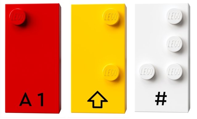 tre mattoncini lego in braille con la lettera A, una freccia verso l'alto e un hashtag