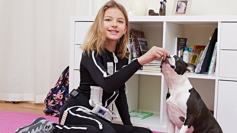 bambina in camera gioca col cane mentre indossa la tuta exopulse 