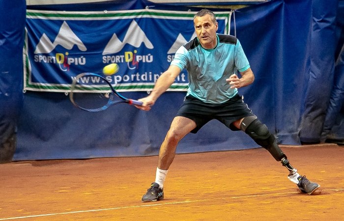un uomo con protesi alla gamba sinistra mentre gioca a para standing tennis