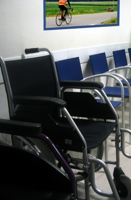 carrozzina vicino ad altre sedie in uno studio medico