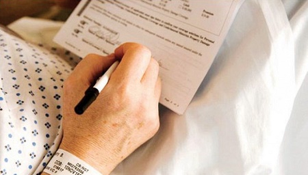 mano di persona in ospedale mentre compila un documento