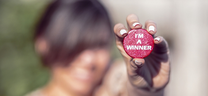 una ragazza mostra un tappo di bottiglia su cui c'è scritto "I'm a winner"