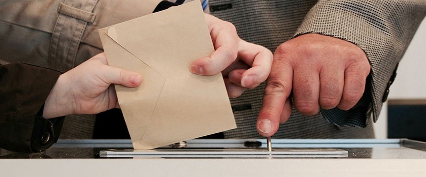 dettaglio delle mani di un elettore che inbuca il voto nell'urna
